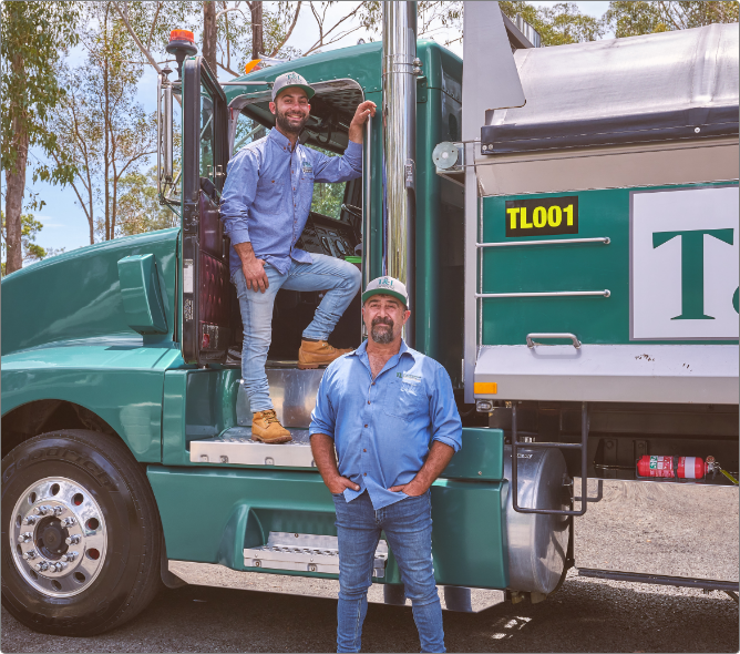 Two men standing in front of a green semi truck.