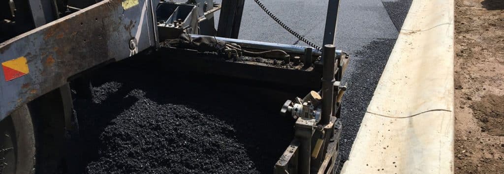 A truck is laying asphalt on a road.