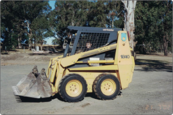 A yellow skid steer parked in a dirt lot.