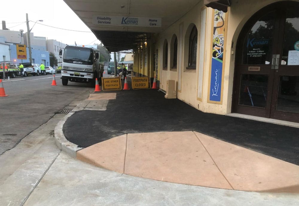 An image of a sidewalk with a sign on it.