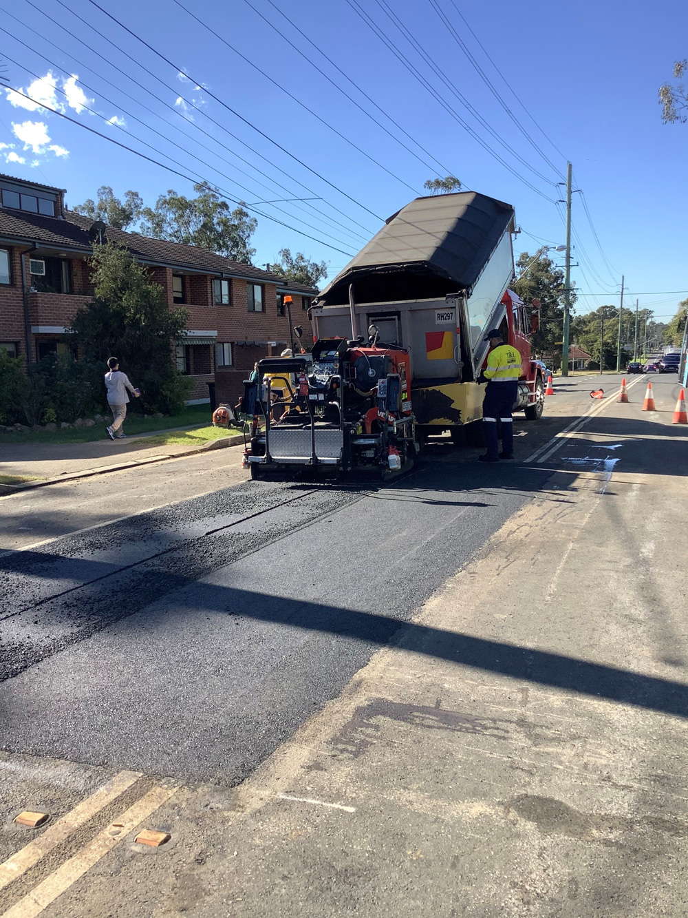 A truck is laying asphalt on a street.